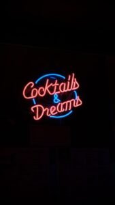 Bright neon Cocktails & Dreams sign in Lisbon, Portugal. Vibrant nightlife atmosphere.