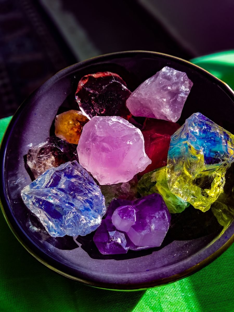 A vivid display of colorful gemstones in a dark bowl, showcasing the beauty of natural crystals.