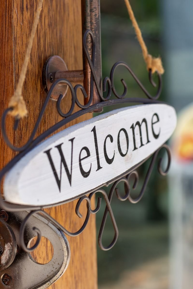Charming close-up of a rustic welcome sign hanging on a wooden door, creating a warm inviting ambiance.