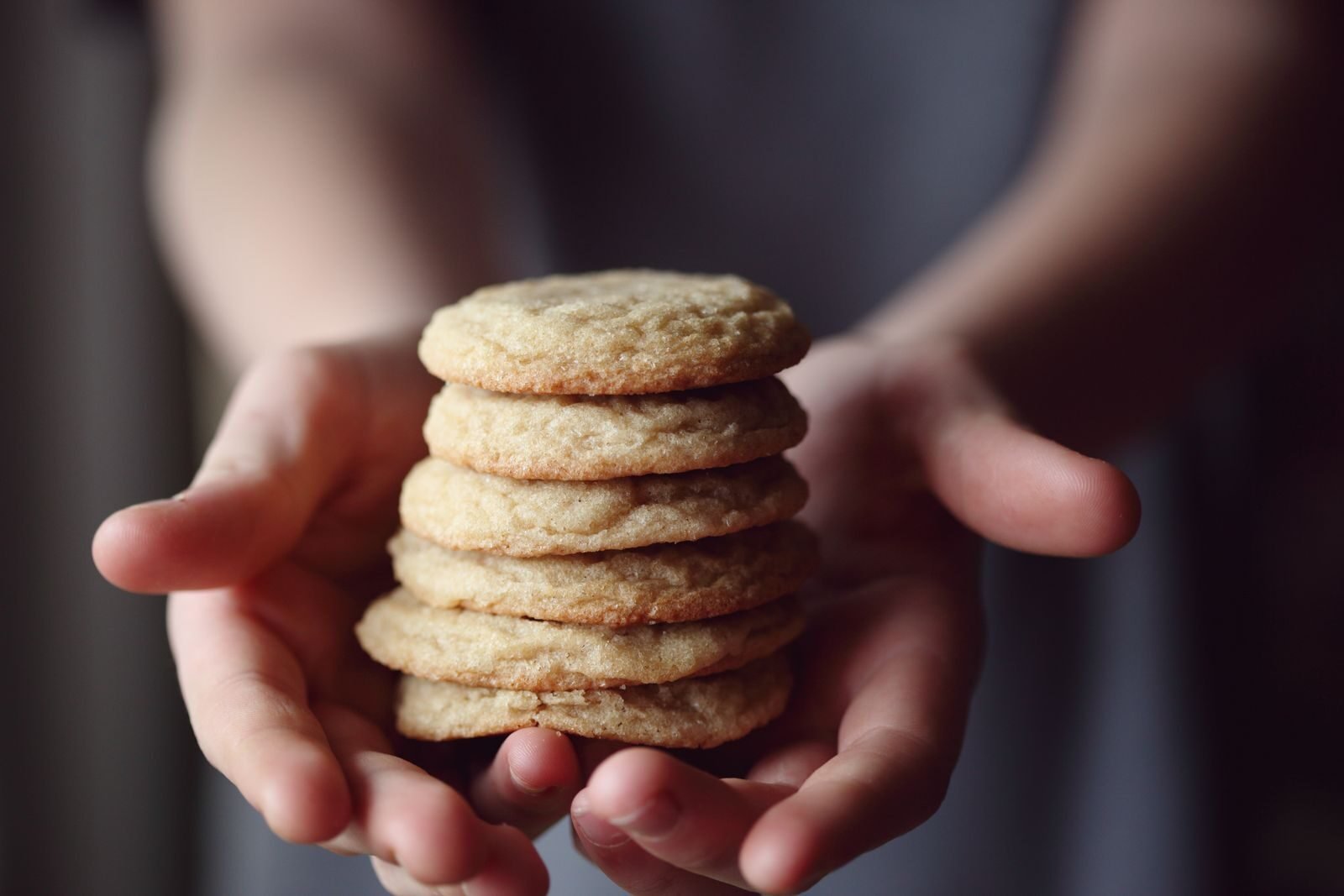 A stack of freshly baked cookies held in hands, capturing a homemade snack vibe.