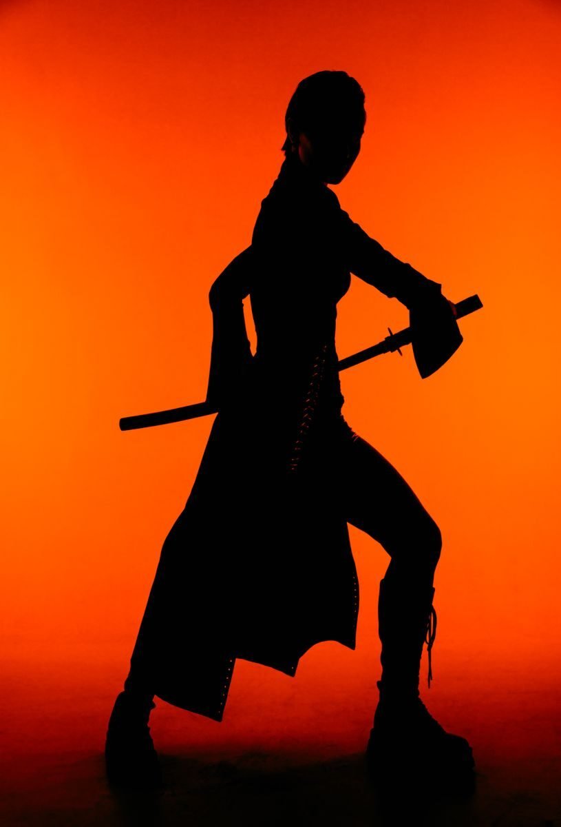 Dynamic silhouette of a woman holding a sword against a red background.