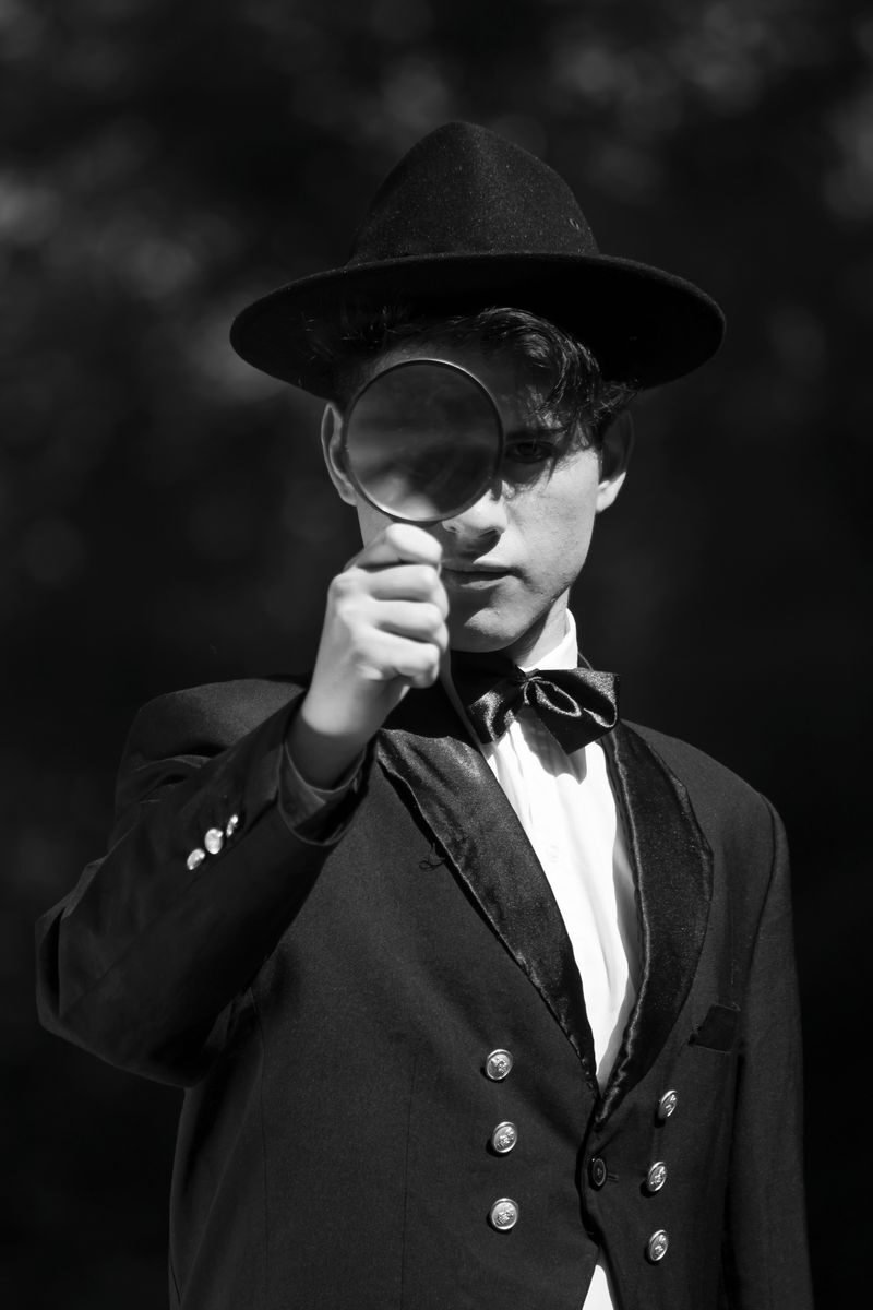 Vintage-inspired portrait of a young man examining through a magnifying glass.