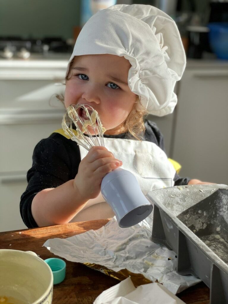 a little girl wearing a chef's hat and holding a whisk