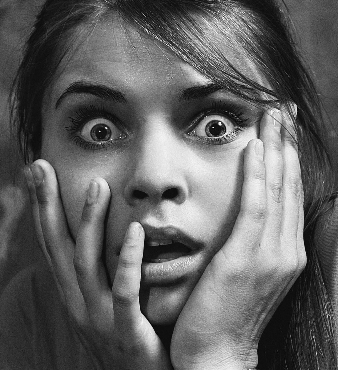 Close-up of a woman expressing shock and surprise in black and white.