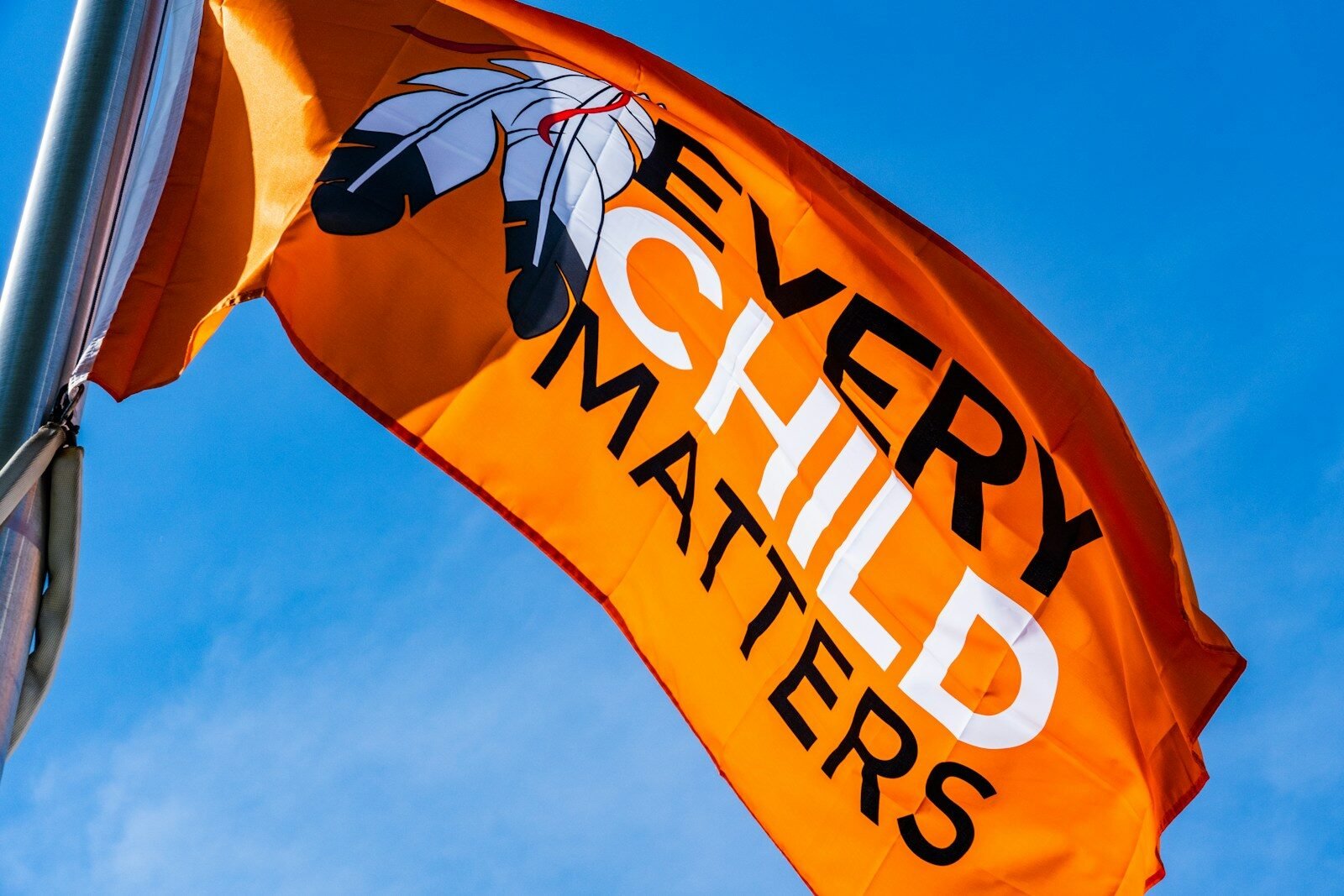 a very large orange flag flying in the sky