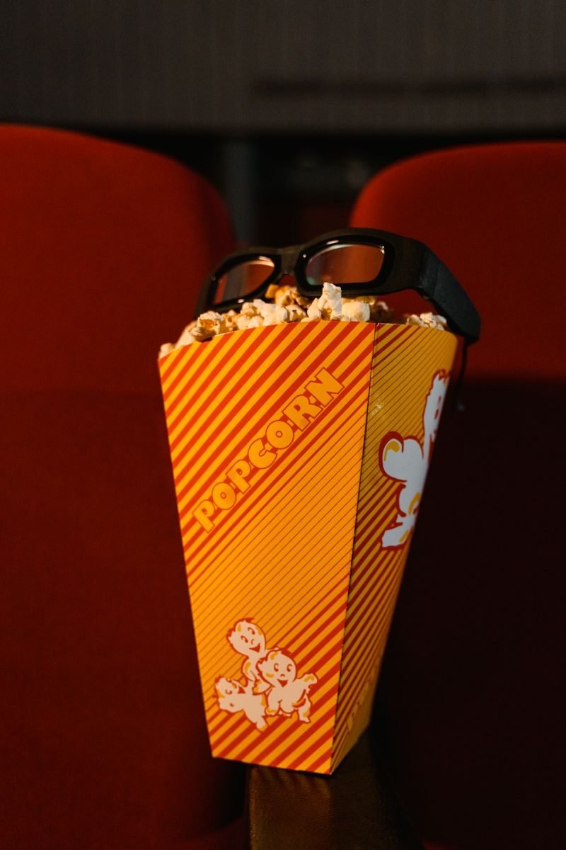 Bucket of popcorn with 3D glasses on a theater seat, ready for a movie experience.